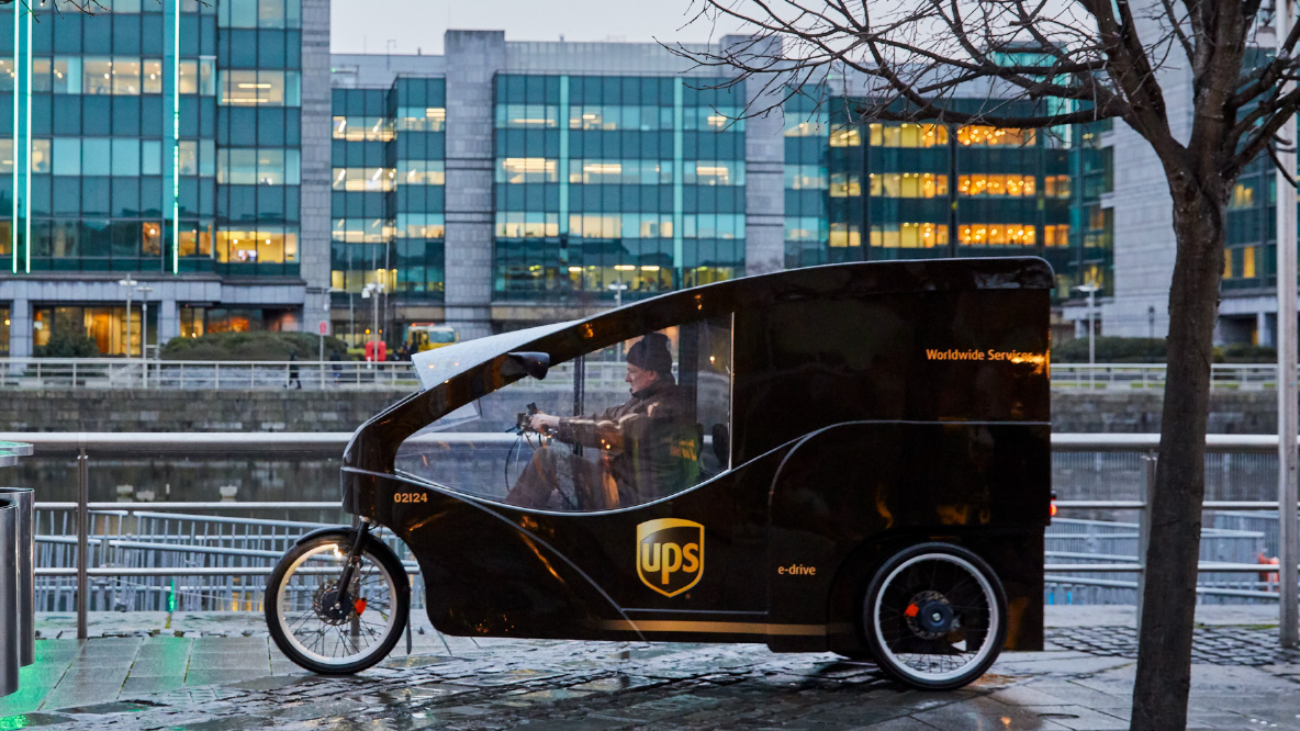 Man driving UPS delivery trike on wet street