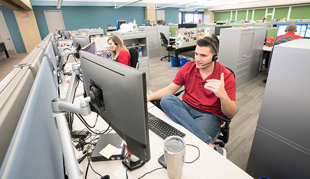 Man sitting in front of computer in a customer service center environment