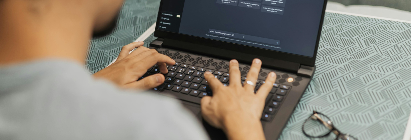 Close-up of a person typing on a laptop with an AI chat interface open on the screen.