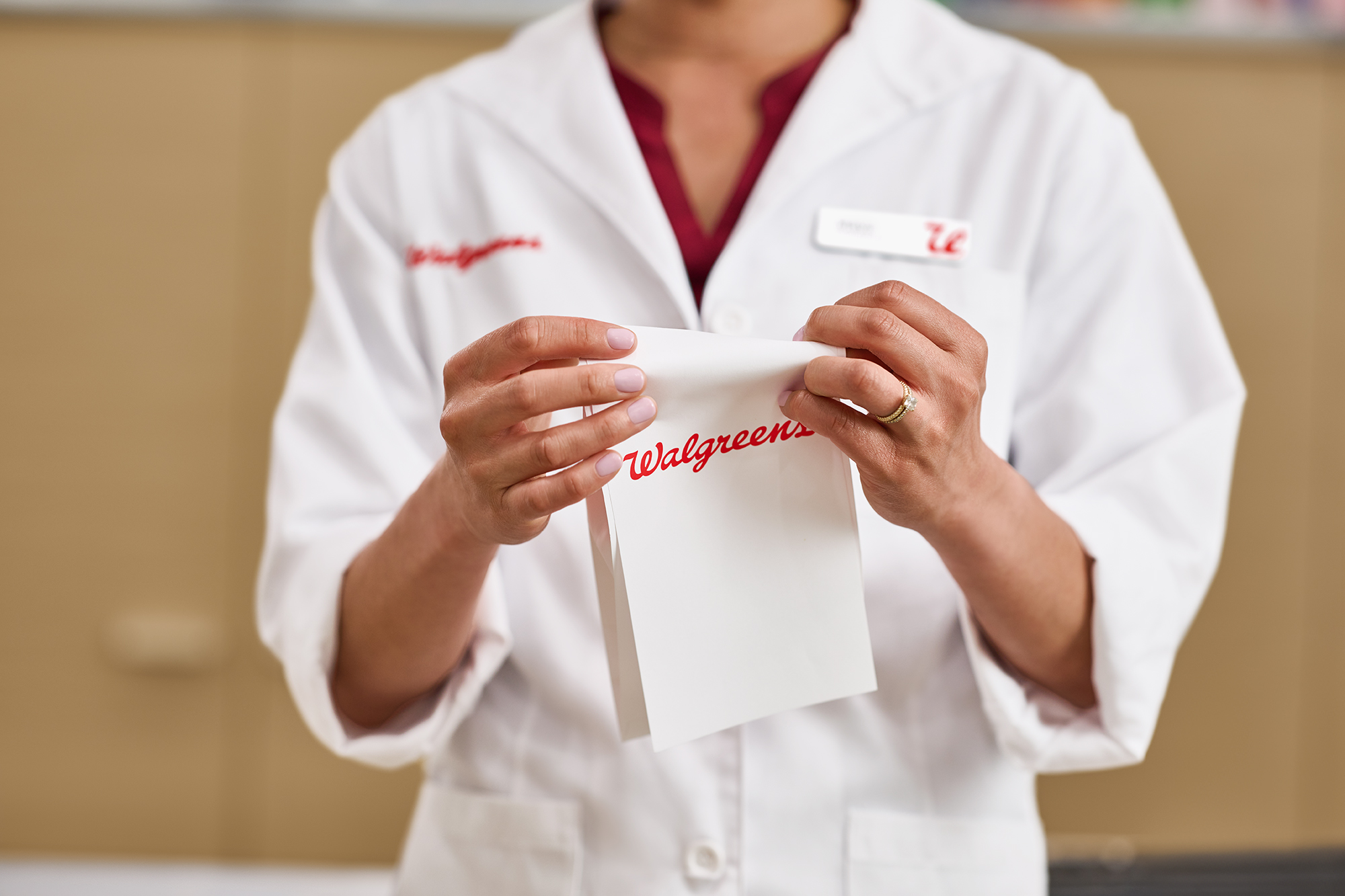 Pharmacist in a white coat holding a prescription bag