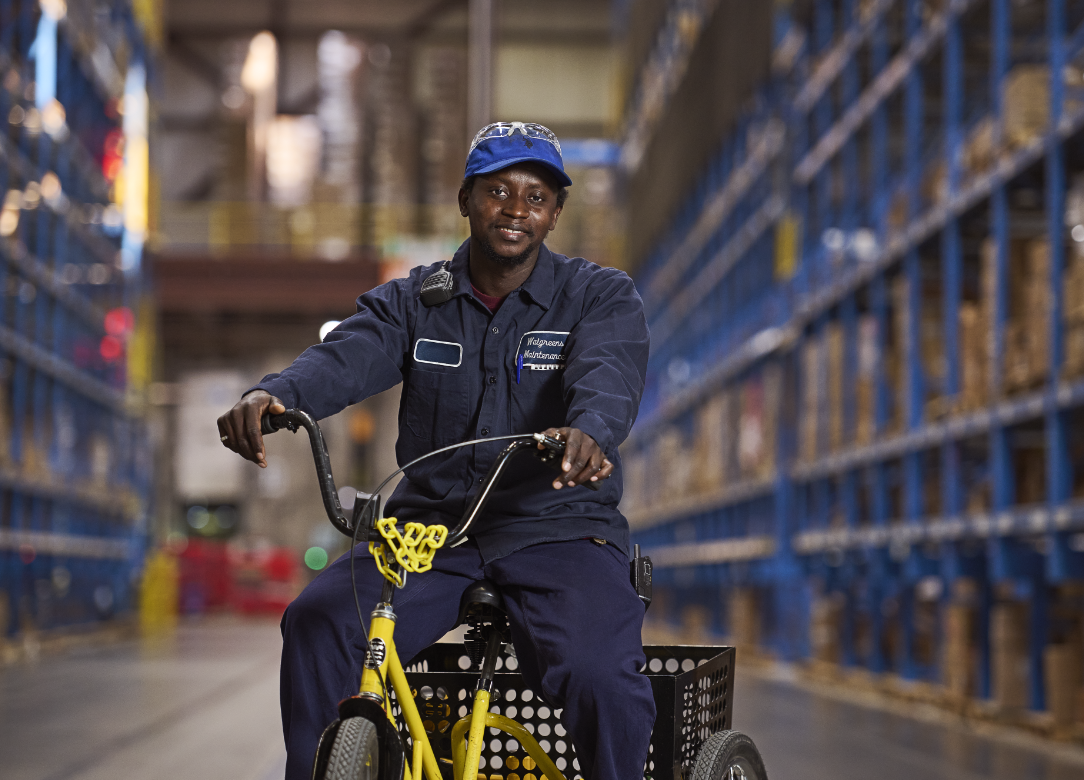 Team member in blue uniform on a yellow bike in a warehouse