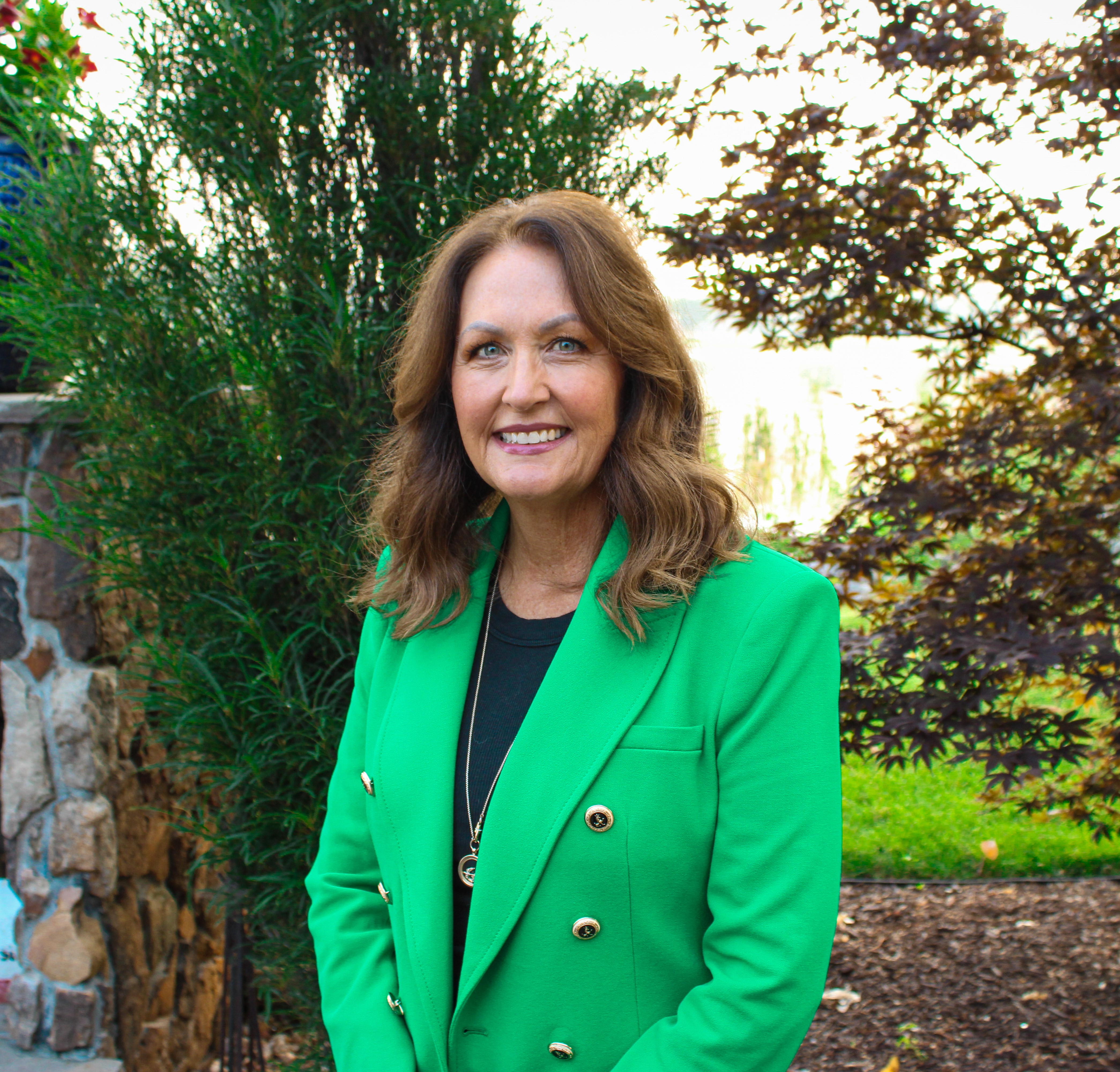 Tracie in a green jacket standing outside