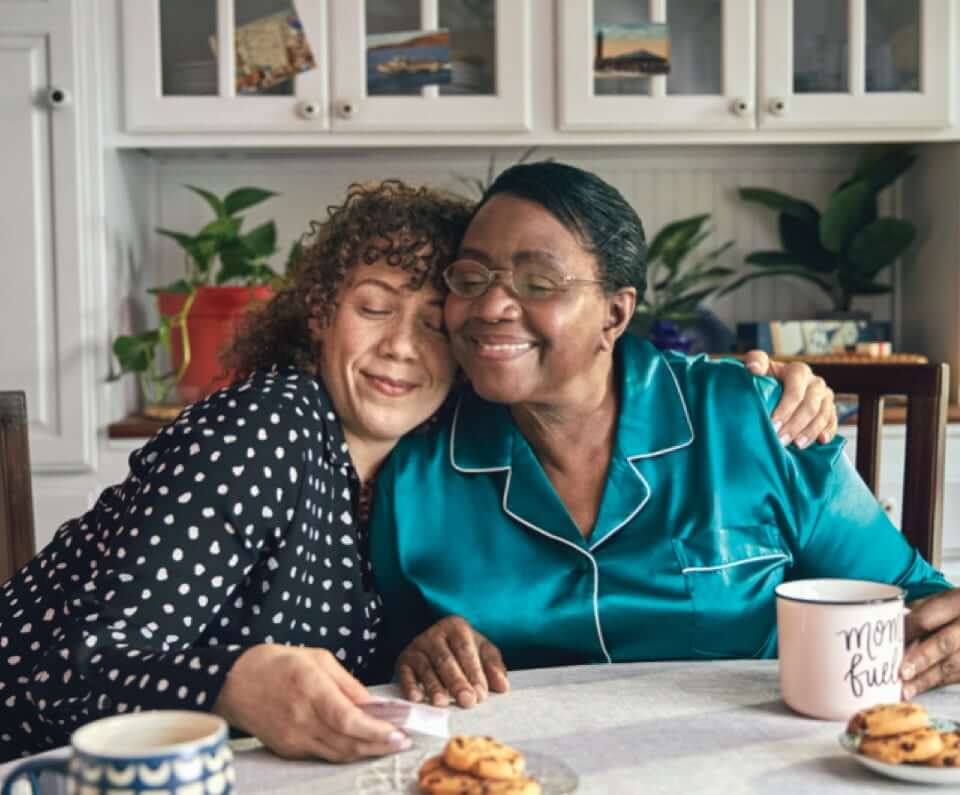 Two women hugging at a dining table