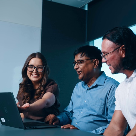 Erin pointing at laptop screen with colleagues