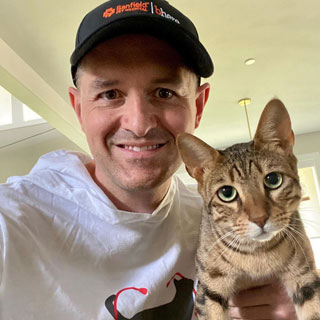 Thumbnail: A person wearing cap and holding a cat with him