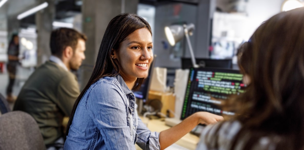 A woman smiling while focused on her computer screen