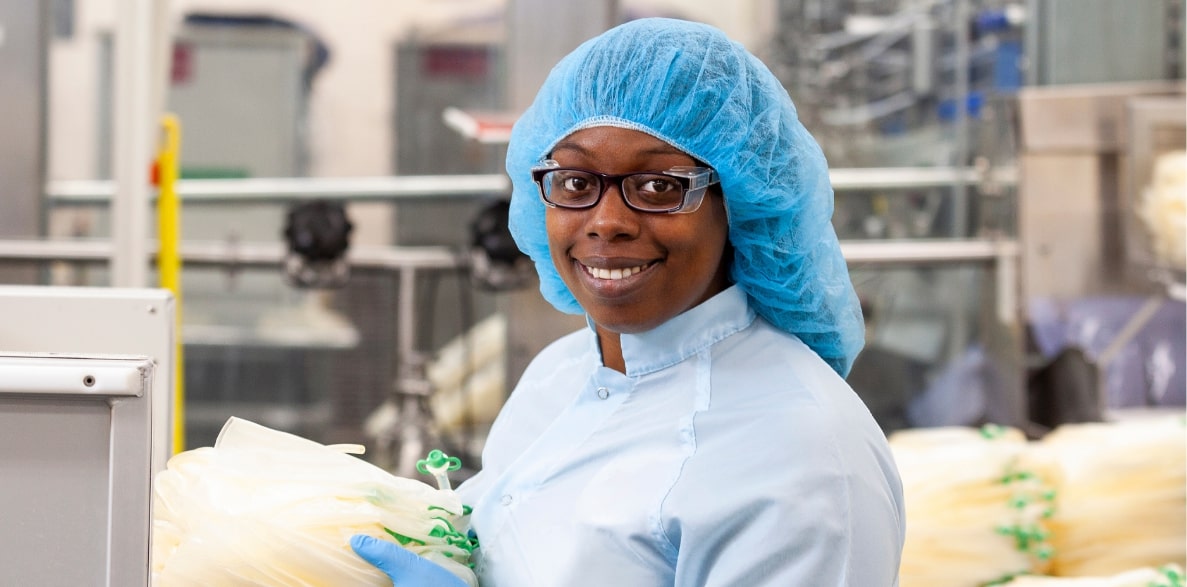 A smiling woman in manufacturing attire