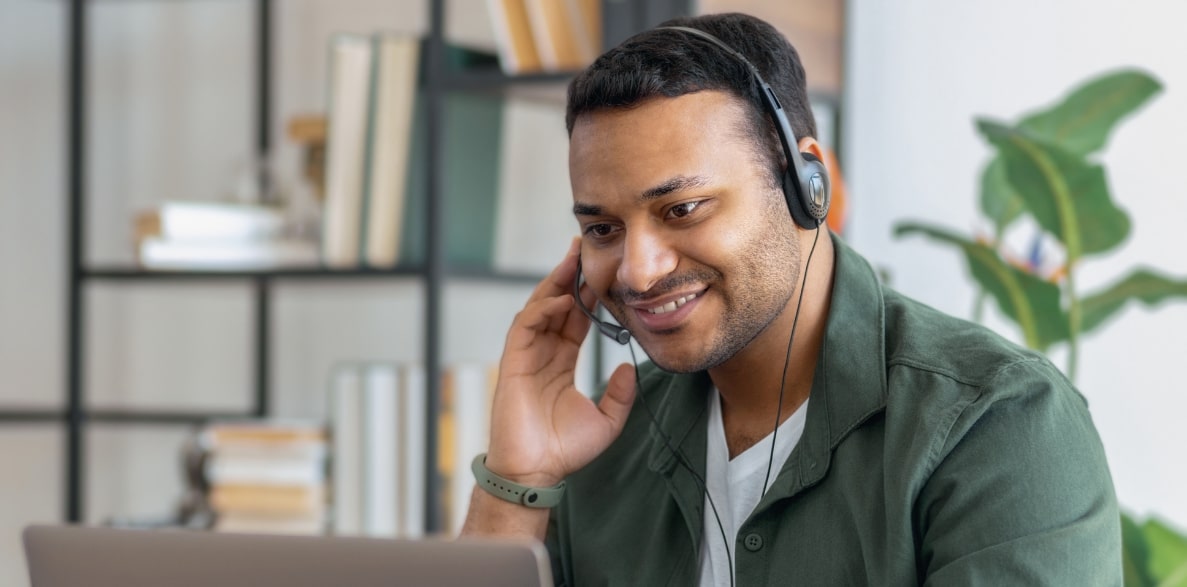 A man working on his laptop with a headset on
