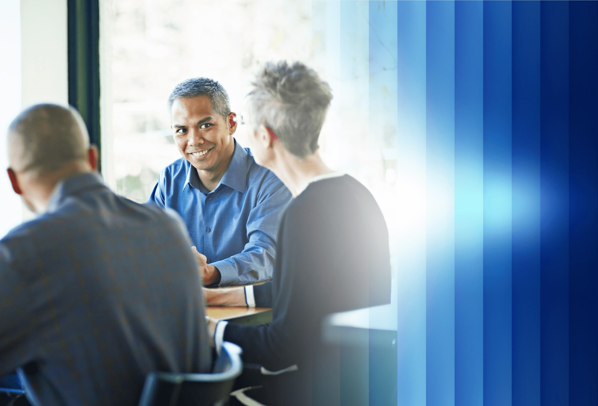 Three Baxter employees, two men and a woman, collaborate using a laptop
