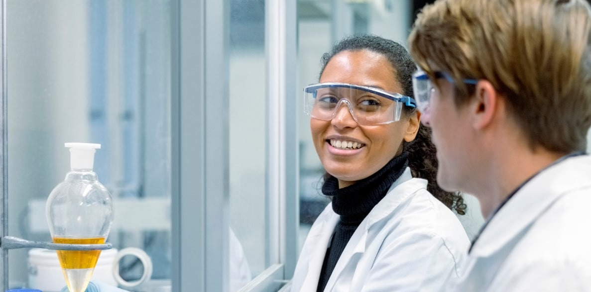 Two scientists wearing lab coats and safety glasses