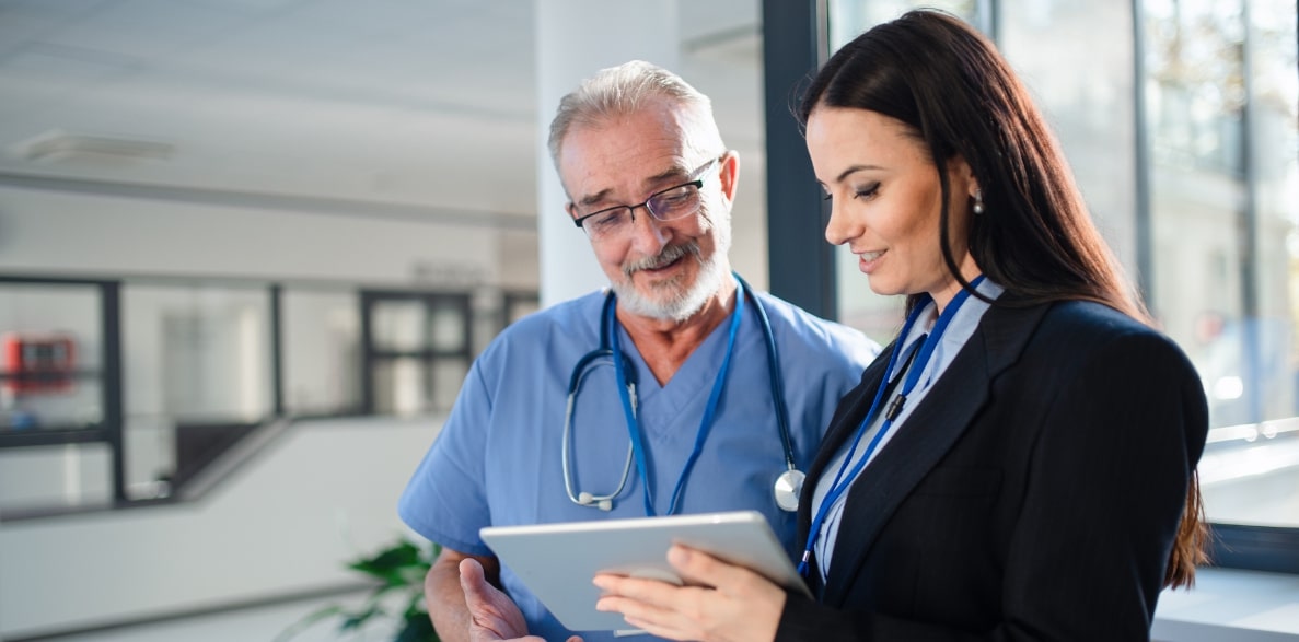 A man and woman in a hospital examining a tablet device
