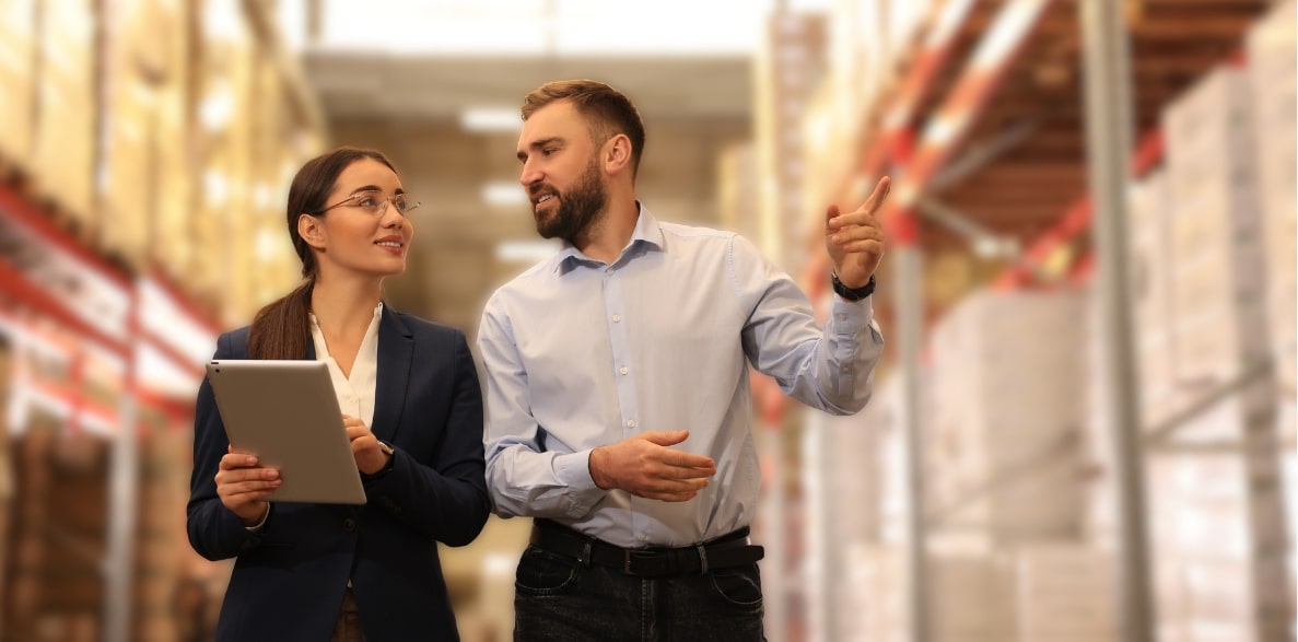 A man and woman in a warehouse, using a tablet to manage inventory and track shipments