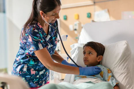 Nursing placing stethoscope on child patient