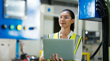 Female worker wearing safety gear and working on laptop