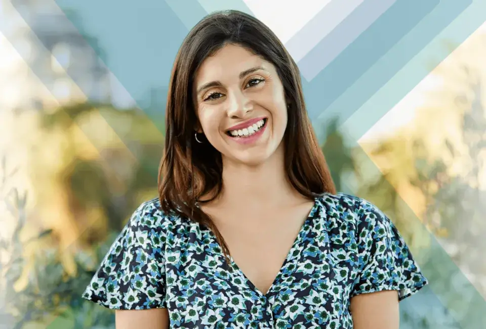 A smiling woman with medium-length dark hair wearing a blue floral blouse