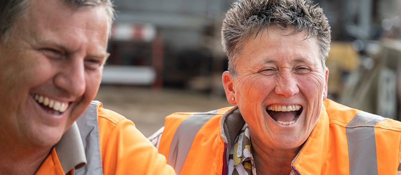 Two people wearing safety vests laughing