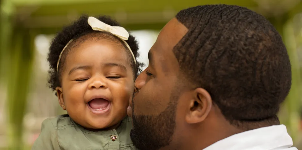 A father kissing his baby daughter on the cheek