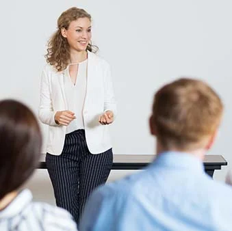 A woman with curly hair giving a training presentation in front of a group