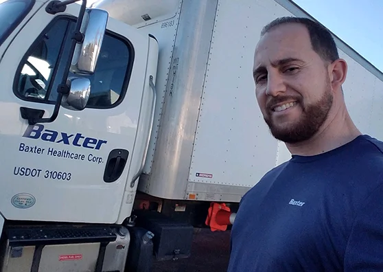 Pedro Perez standing in front of a Baxter delivery truck