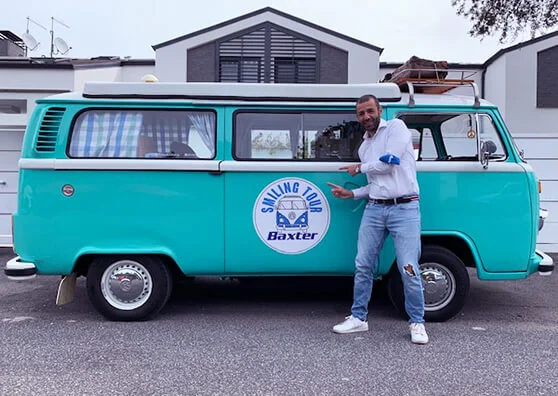 A man standing in front of the Baxter Smiling Tour van