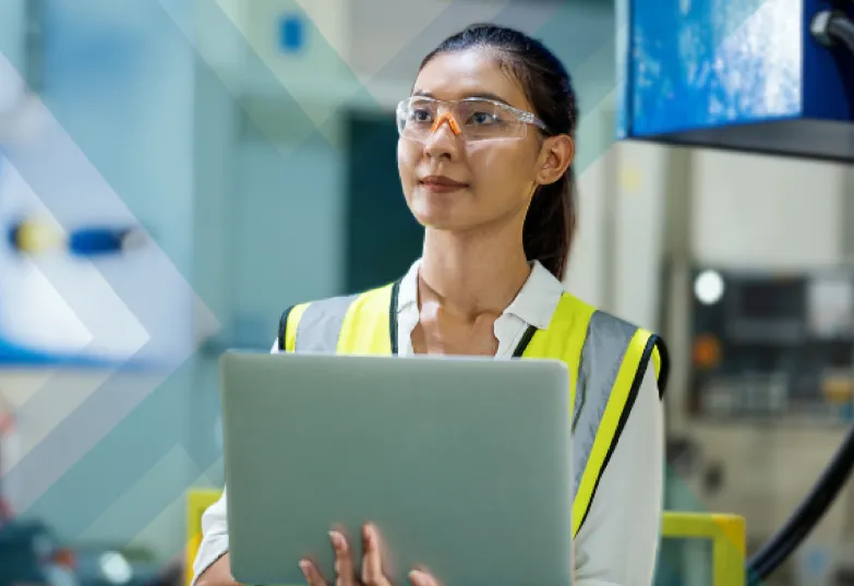 A woman in a safety vest holding a laptop, ready to work in a secure environment