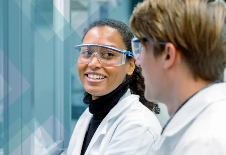 Two scientists wearing lab coats and safety glasses