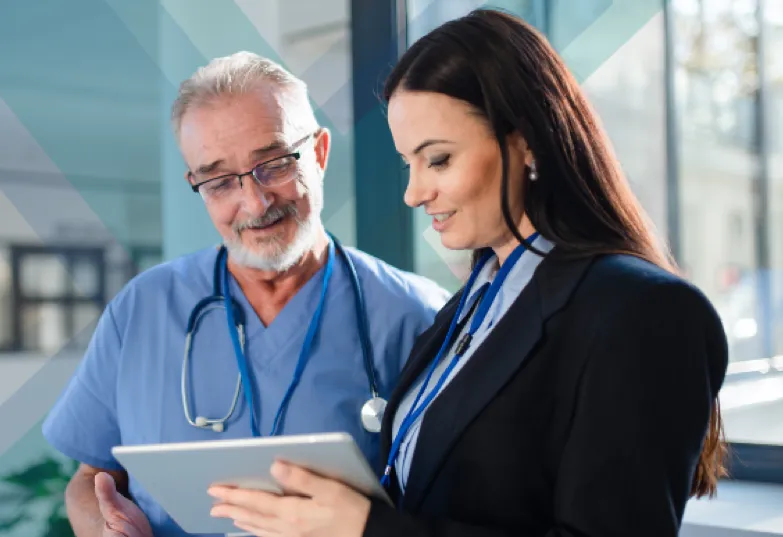 A man and woman in a hospital examining a tablet device