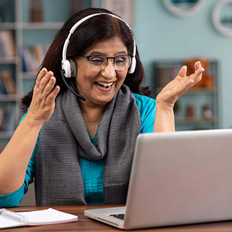 Woman with headphones on talking to someone via her laptop