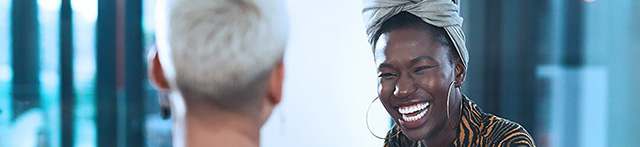 This image showcases a joyful interaction between two individuals, with one person smiling brightly in a dynamic, modern indoor setting.