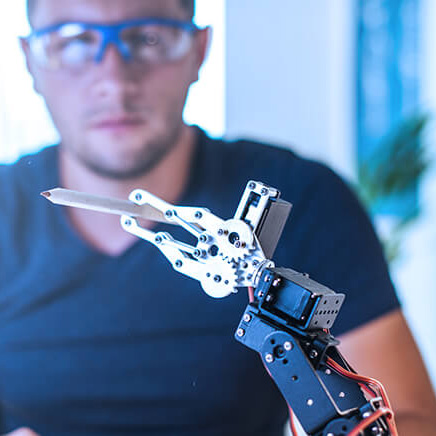 This image highlights innovation and technology, featuring a focused professional working with a robotic arm in a modern setting