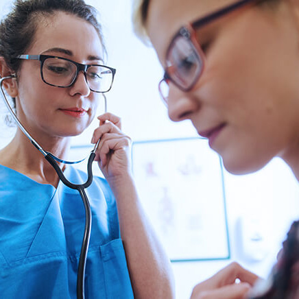 This image depicts a healthcare professional attentively using a stethoscope to examine a patient in a clinical setting