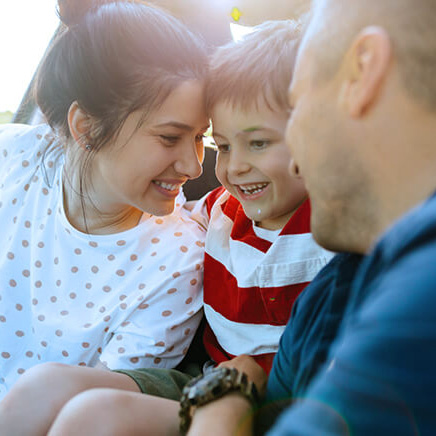 This image captures a tender family moment with parents and a young child sharing smiles and closeness