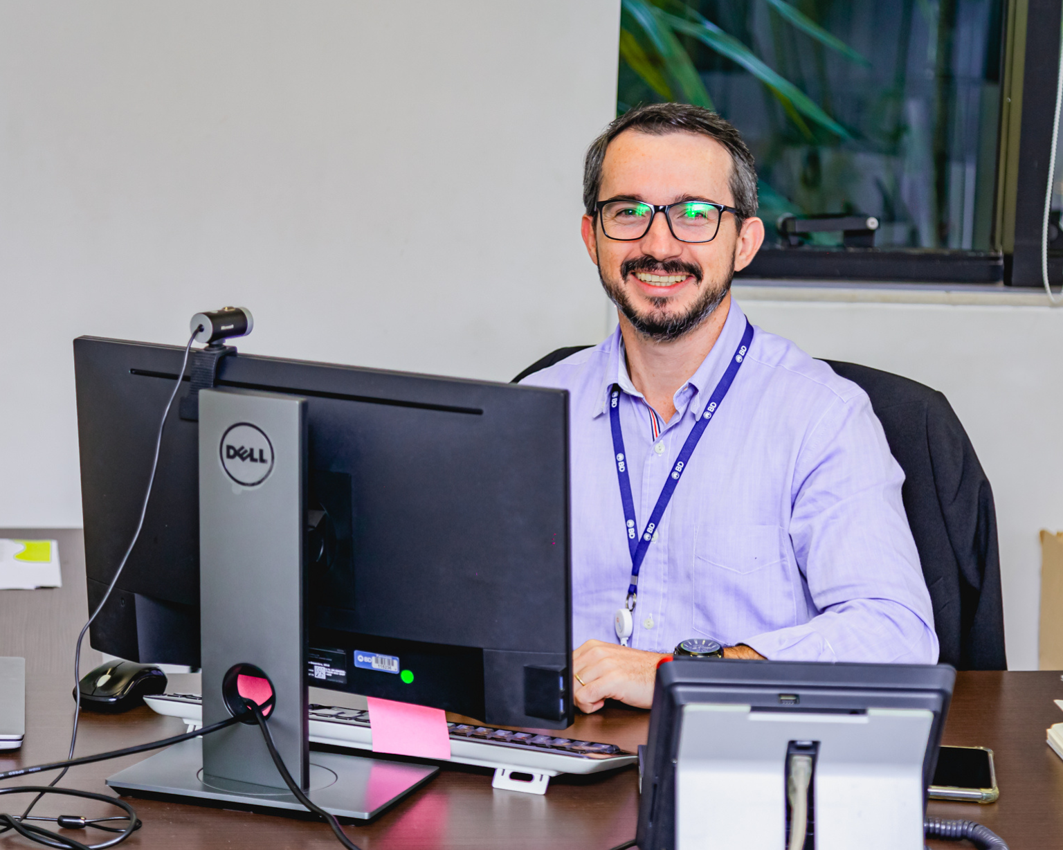 Empleado de BD sentado en un escritorio, trabajando en una computadora en una oficina.