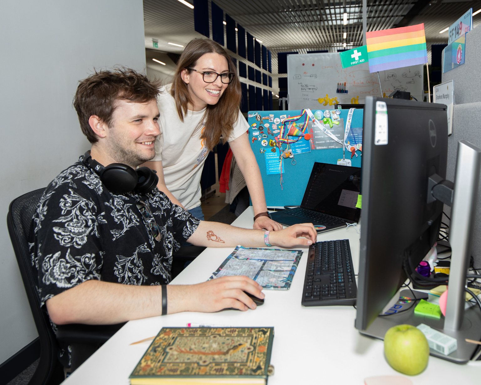 Dos colegas de BD colaborando en un escritorio dentro de un espacio de trabajo moderno.