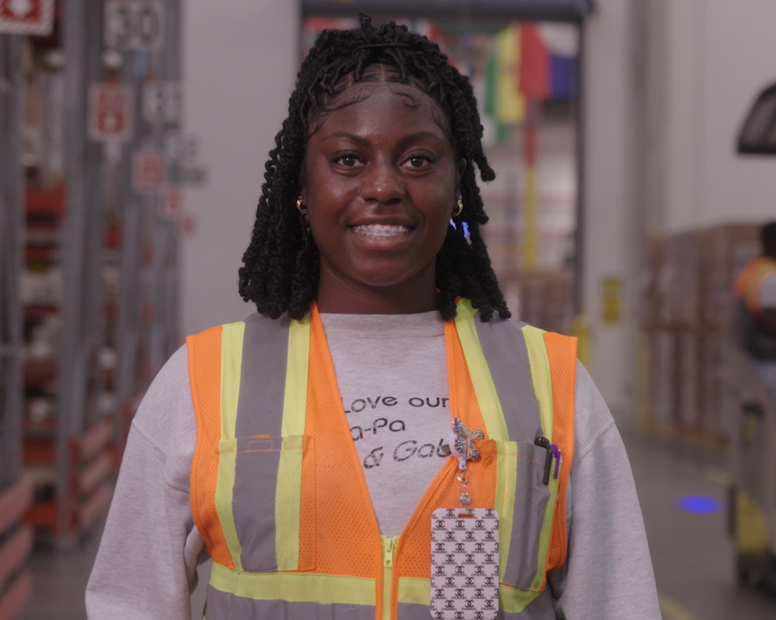 Empleado de BD con chaleco de seguridad, de pie dentro de un centro de distribución.