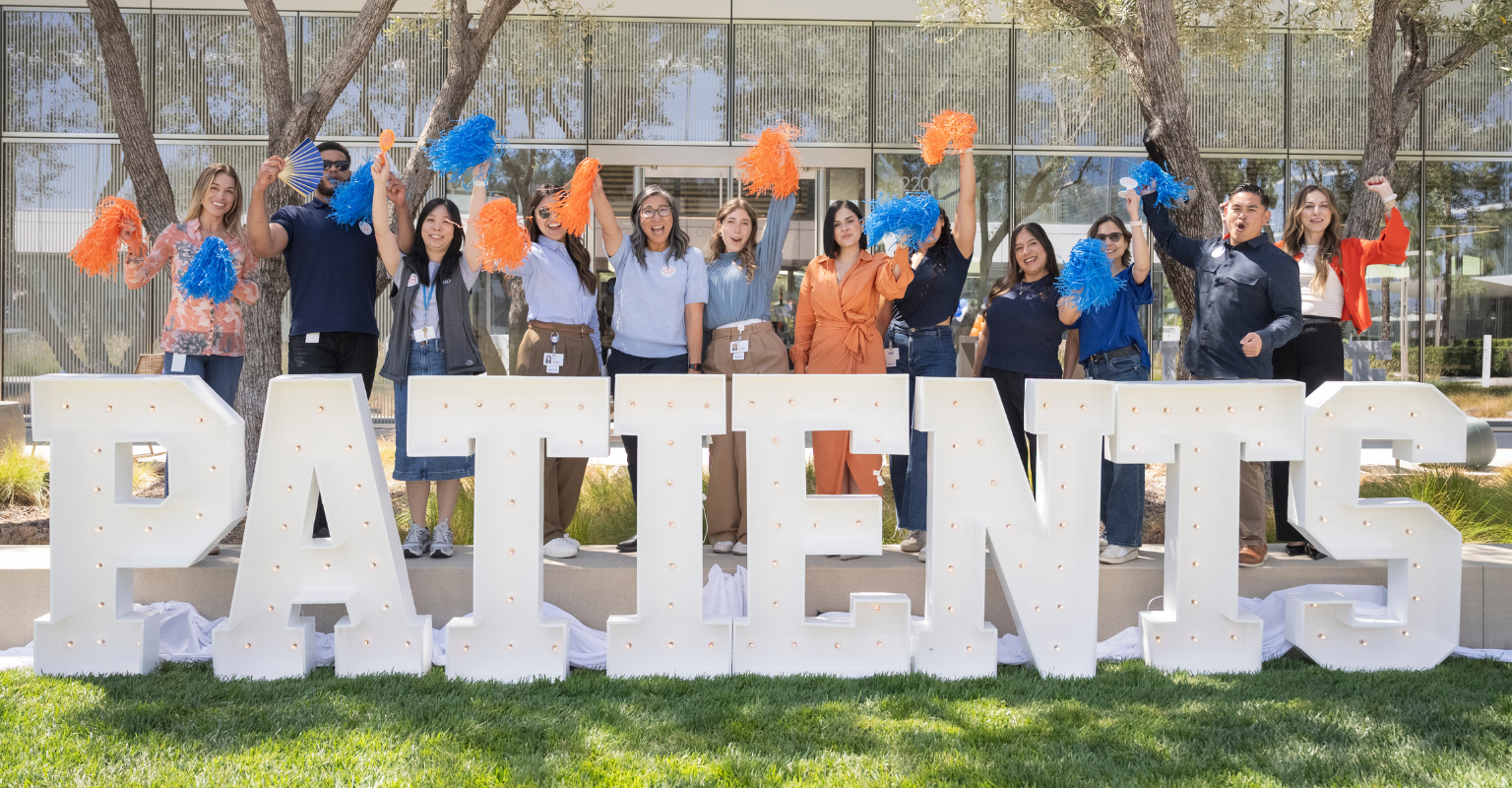 BD associates celebrating together outdoors in front of large &ldquo;PATIENTS&rdquo; letters.