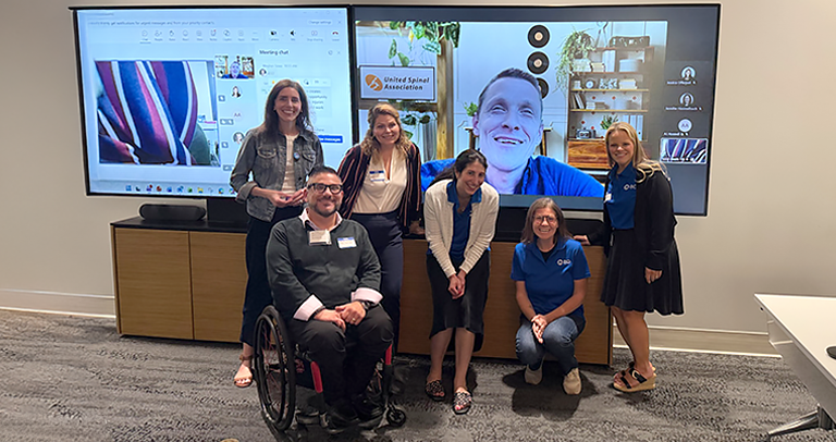 BD associates and local non-profit partners participating in a hybrid meeting, with in-person and virtual attendees displayed on large screens.