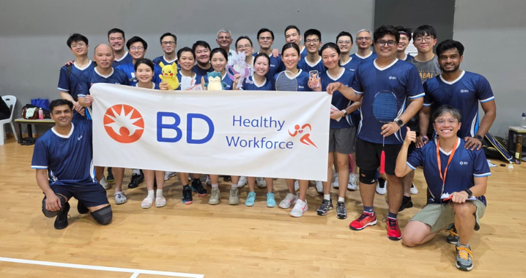 BD associates posing with a Healthy Workforce banner at a team sports event.