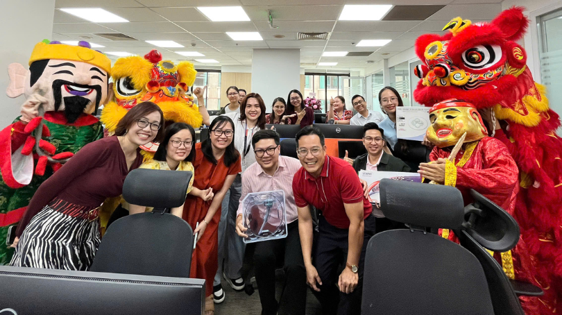 BD associates in Vietnam posing with traditional dance performers during a workplace celebration.