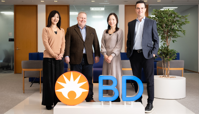 Four associates smiling in front of a BD sign