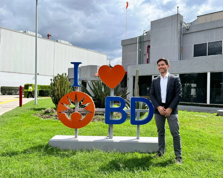 Associate standing beside an “I Love BD” sign outside a BD facility.
