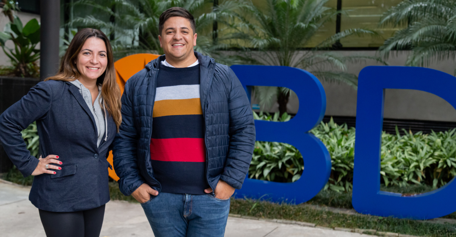 Two BD associates standing beside a BD sign in an outdoor courtyard.