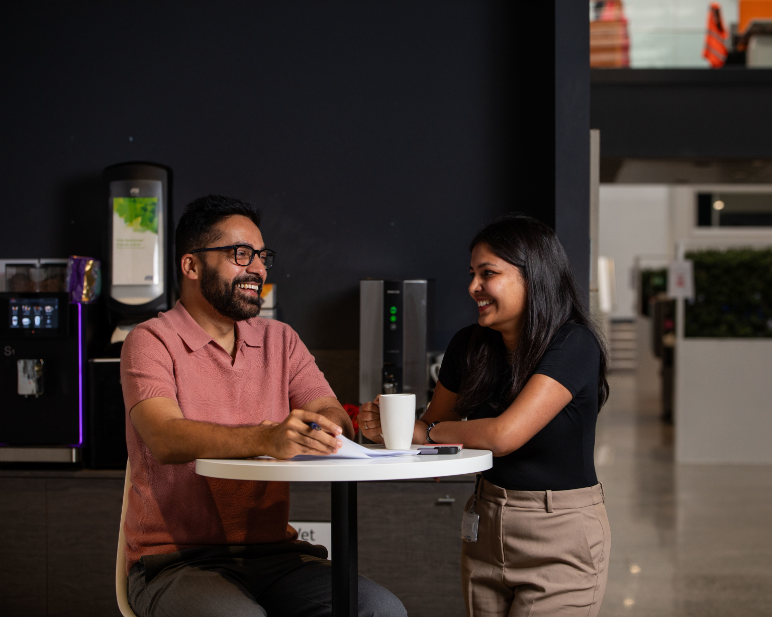 Dos BD associates conversando en una mesa pequeña dentro de un café de trabajo moderno en la oficina de BD en Limerick.