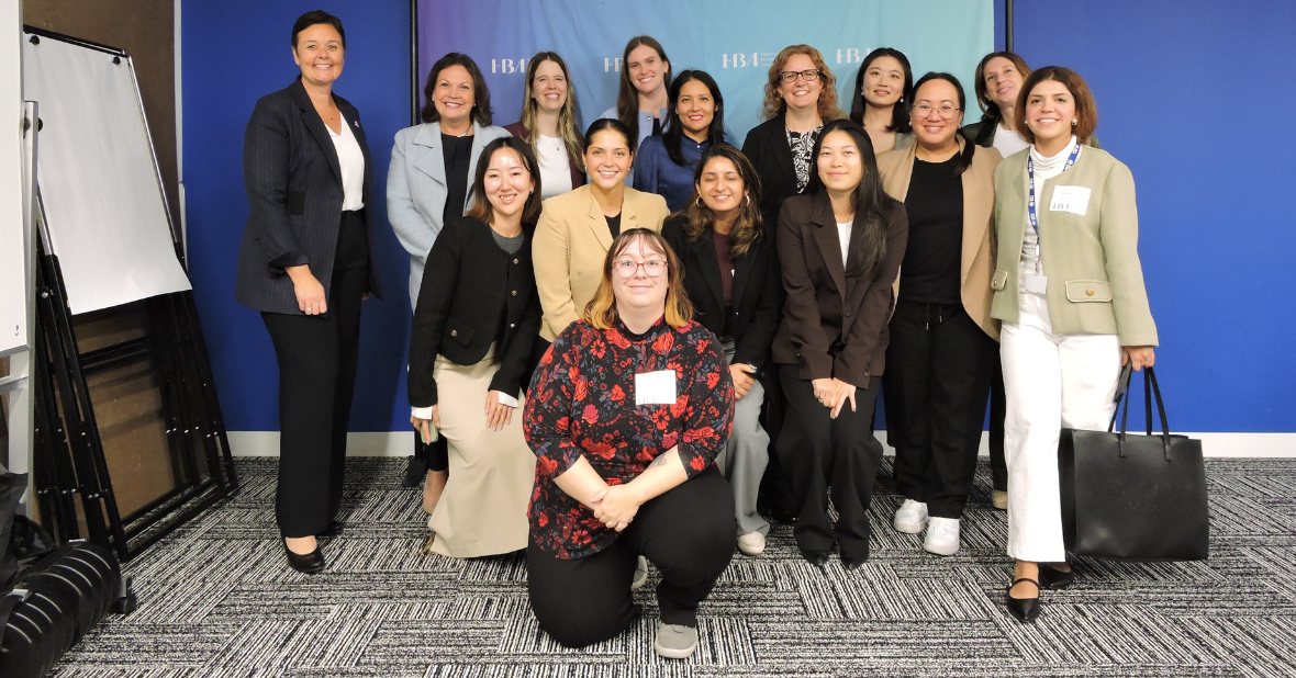 Groupe de personnes associées de BD posant ensemble lors d’un événement professionnel, devant un mur bleu avec la marque HBA.