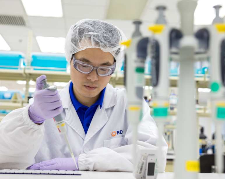 Persona en un entorno de laboratorio, con gafas y una redecilla protectora para el cabello.