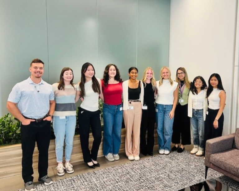 Un grupo numeroso de asociados de BD en un entorno interior, sonriendo a la cámara.