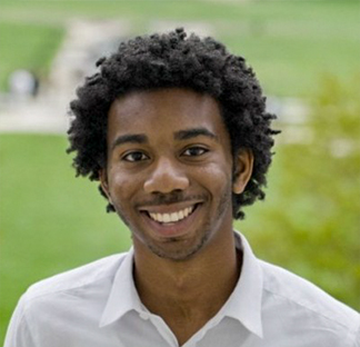 Una persona con una camisa blanca de cuello, de pie al aire libre, con un paisaje de césped y un sendero borrosos de fondo.