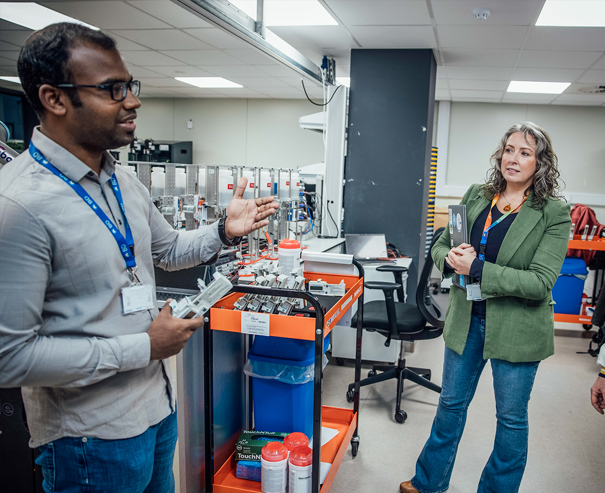 Dos individuos colaborando dentro de la carcasa de una máquina industrial, mientras inspeccionan y ajustan componentes mecánicos internos.