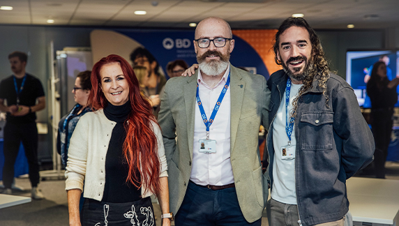 Several individuals standing together in a conference or event space with BD branding visible behind them.