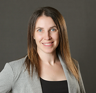 Imagen que muestra a un individuo vistiendo un blazer y una prenda superior oscura, posando frente a un fondo oscuro y liso.